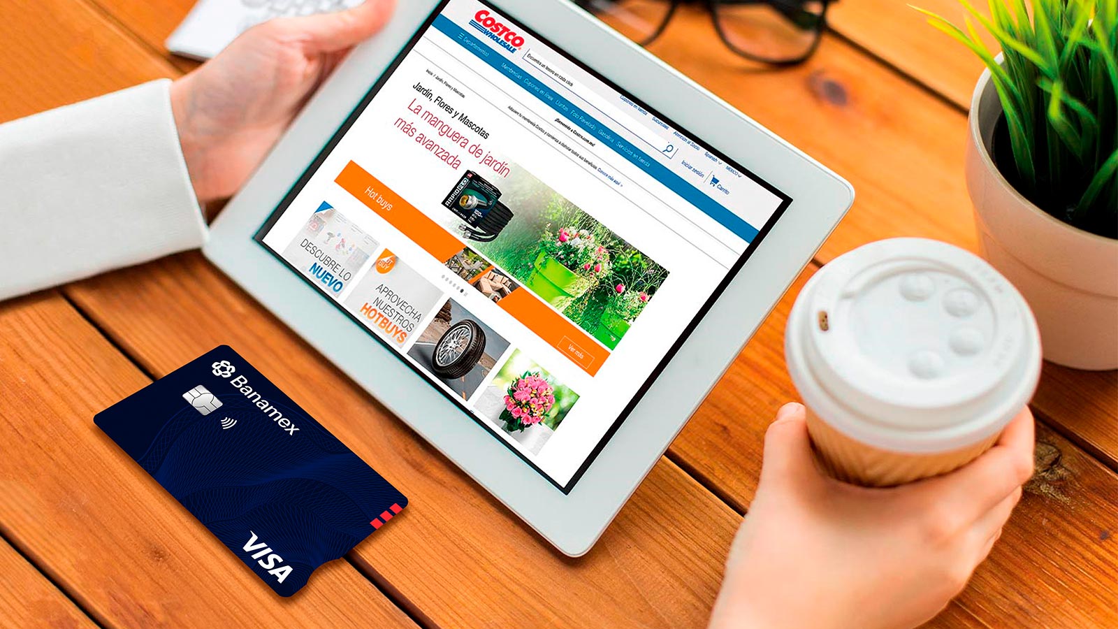 Persona sosteniendo una tablet y tomando un café con la tarjeta Banamex